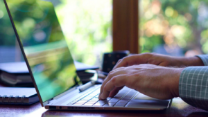 Person's hands are visible typing on a laptop.