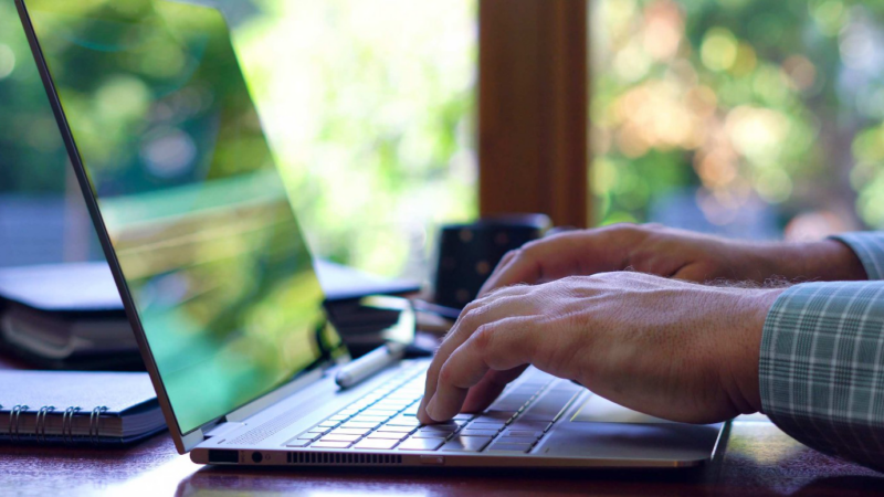 Person's hands are visible typing on a laptop.